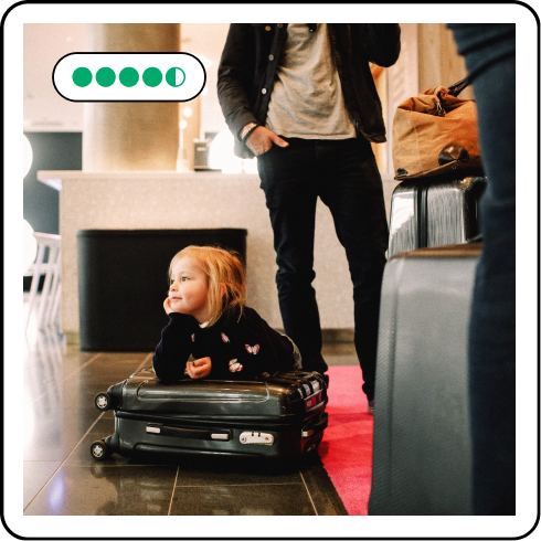 Image description: A child sitting on luggage in a hotel lobby. Five review bubbles are on the upper left corner.