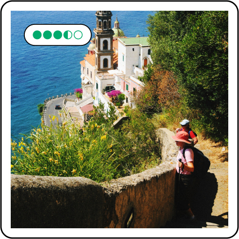 Image description: Two people on a dirt road gazing out into the ocean. Five review bubbles are on the upper left corner.