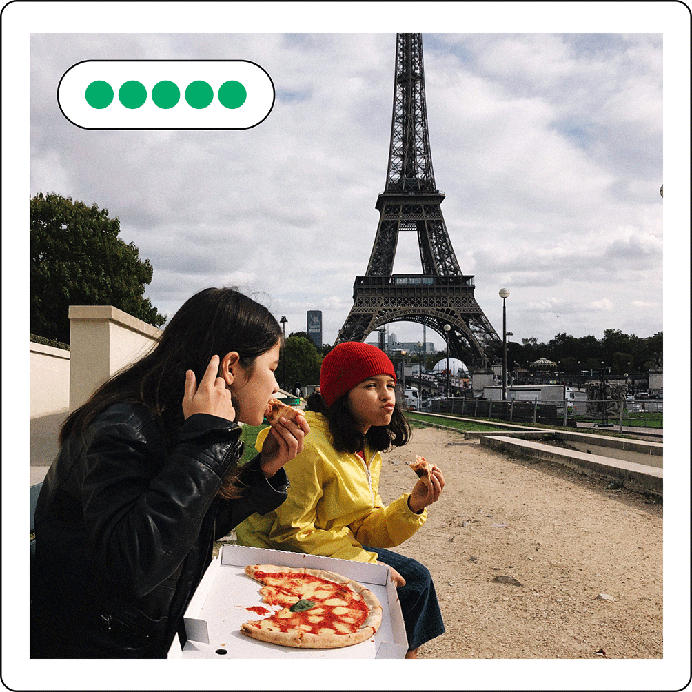 Image description: Two people eating pizza by the Eiffel Tower. Five review bubbles are on the upper left side.