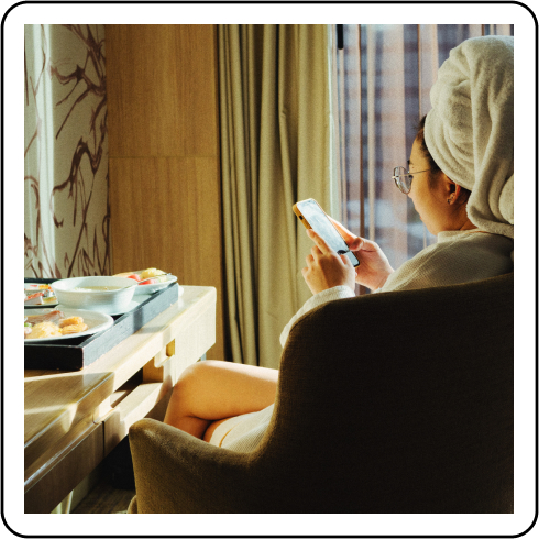 Image description: A person in a hotel room scrolling on their phone.