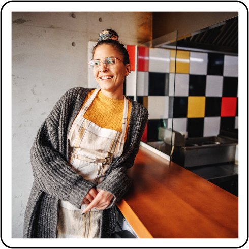 Image description: A person wearing an apron leaning against a counter.