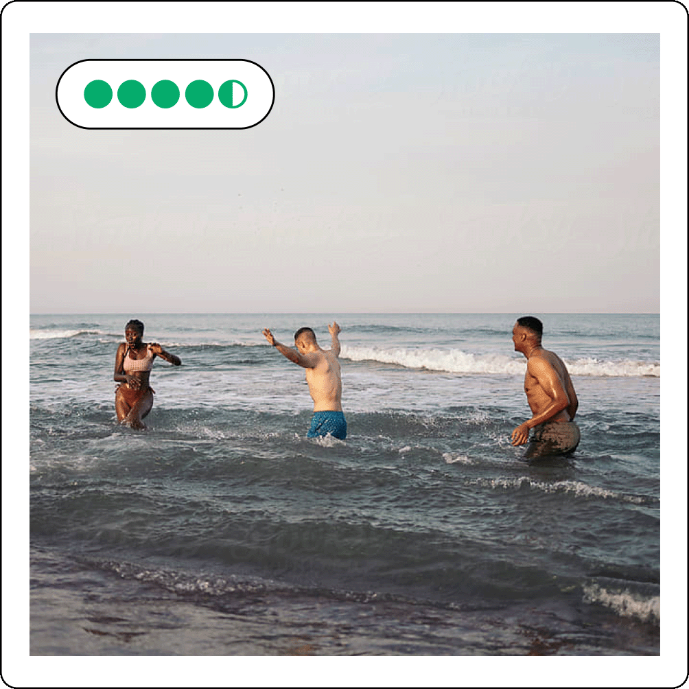 Image description: photo of three people playing in the ocean with bubble rating at the top left corner.